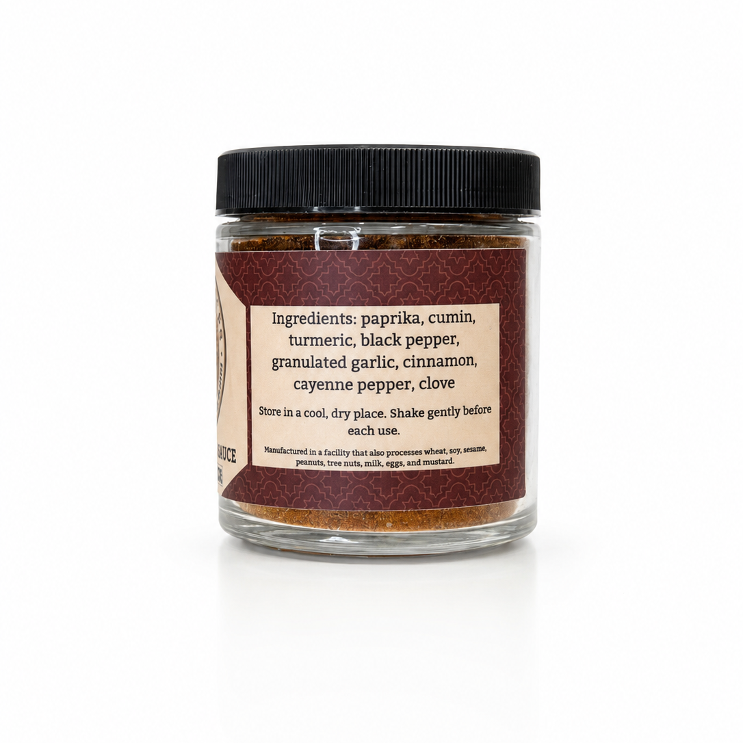 A jar of Old Town Smokehouse Paprika Rub against a white background. The product is in a clear glass jar with a black screw-on lid and a cream-colored label detailing the ingredients: paprika, cumin, turmeric, black pepper, granulated garlic, cinnamon, cayenne pepper, and clove.