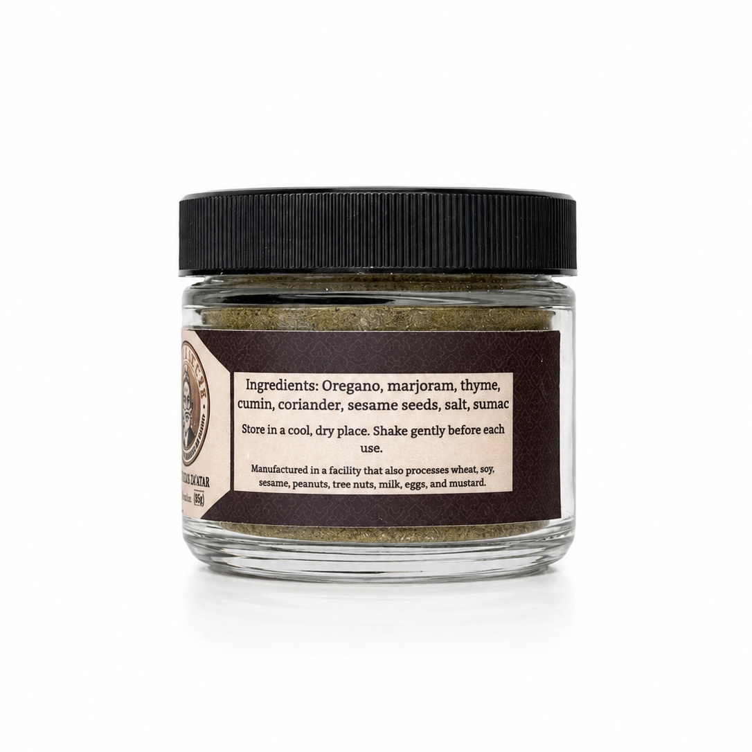 A small clear glass jar of ground spice blend with a black lid and a dark brown label, photographed on a clean white background.
